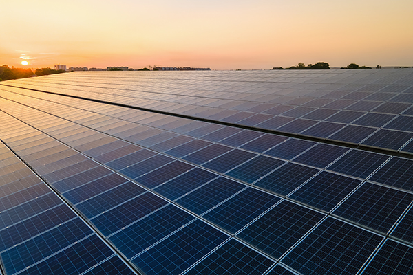 Eine große Photovoltaikanlage auf einem Dach bei Sonnenuntergang